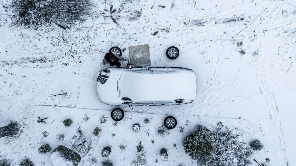 Aerial view of a man changing tires, on a cloudy winter day - top down drone sho