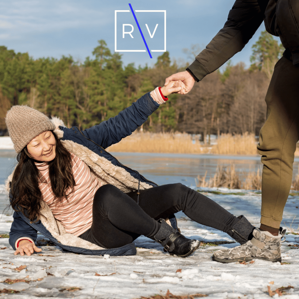 woman slips and falls down on snowy road with man helping her up