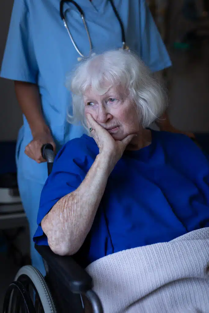 Front view of a Caucasian surgeon pushing the wheelchair of a sad senior female patient in clinic