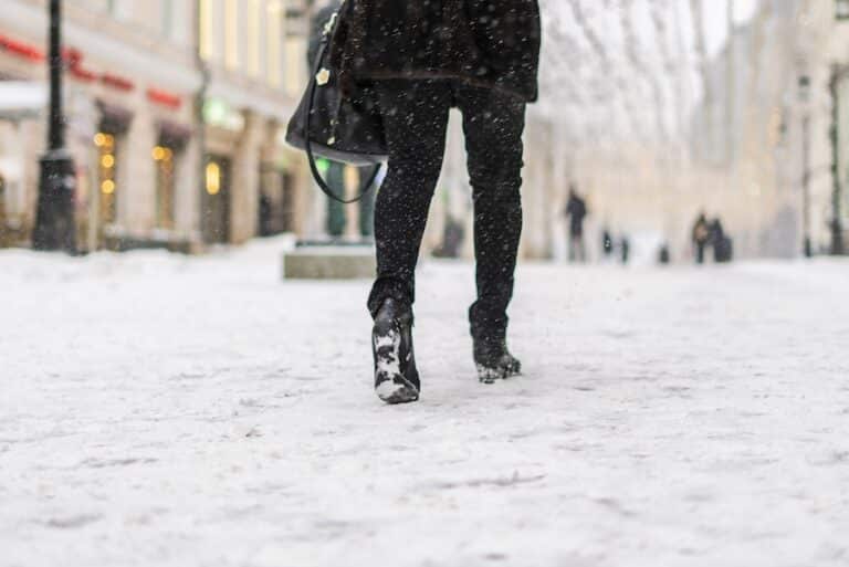 peoples legs with boots walk in snowy day. fashion concept in the city street